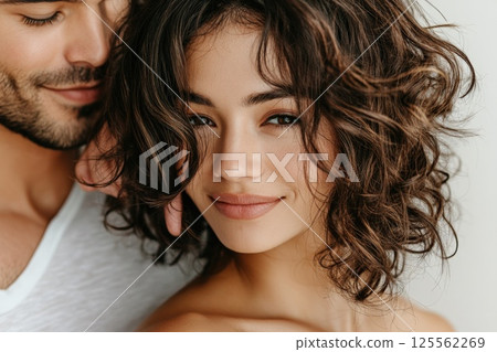 Couple sharing a tender moment while brushing hair in soft indoor lighting 125562269