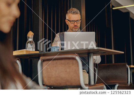 A Focused Professional Engaged in Work on a Laptop within a Modern and Stylish Workspace A Focused Professional Engaged in Work on a Laptop within a Modern and Stylish Workspace 125562323