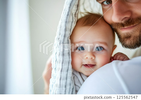 Father enjoys playful moment with baby during peek a boo in bright setting 125562547