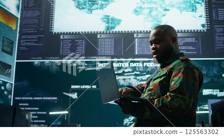 Military team manages cybersecurity operations in a high tech control center base of operations, managing data protection and surveillance systems, safeguarding national security. Camera B. Military team manages cybersecurity operations in a high tech control center base of operations, managing data protection and surveillance systems, safeguarding national security. Camera B. 125563302