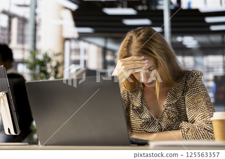 Tired businesswoman showing signs of burnout at her desk, feeling overwhelmed by the demands of her job. Worker struggles with professional challenges and emotional strain, tough day. Tired businesswoman showing signs of burnout at her desk, feeling overwhelmed by the demands of her job. Worker struggles with professional challenges and emotional strain, tough day. 125563357