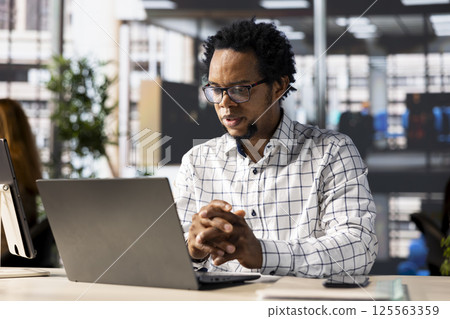 Confident businessman at his office desk working on report writing, financial planning and deadline management. Expert specialist reviewing objectives and goals to ensure success. Confident businessman at his office desk working on report writing, financial planning and deadline management. Expert specialist reviewing objectives and goals to ensure success. 125563359