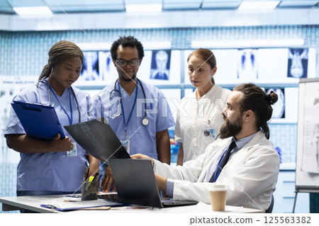 Group of healthcare workers analyzing diagnostic data and planning treatment in a modern private clinic, emphasizing collaboration. Coordinating recovery plans and discussing recent test results. 125563382
