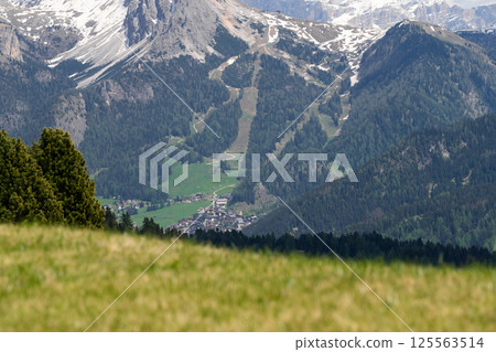 Scenic mountain valley landscape with snow-capped peaks and verdant forests in springtime near Valley of Funes at Dolomites, Italy 125563514