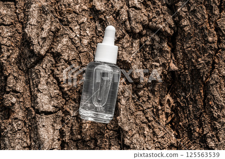 Transparent glass dropper serum bottle with bakuchiol and peptides on tree bark surface Transparent glass dropper serum bottle with bakuchiol and peptides on tree bark surface 125563539