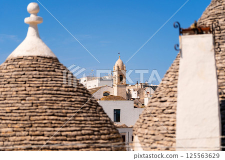 Trulli rooftops with bell tower in the background Trulli rooftops with bell tower in the background 125563629
