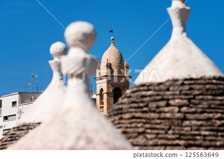 Trulli rooftops with bell tower in the background 125563649