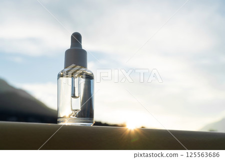 Dropper Bottle with Mountain and Water Backdrop at Sunset Dropper Bottle with Mountain and Water Backdrop at Sunset 125563686