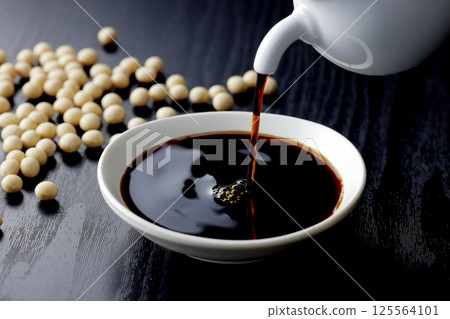 Pour soy sauce into a small plate 125564101