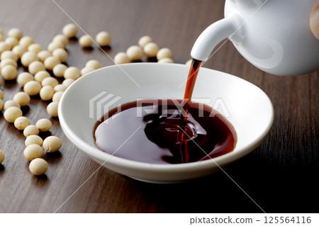 把醬油倒在一個小盤子裡 把醬油倒在一個小盤子裡 125564116