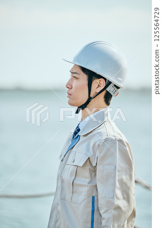 一位 20 多歲的年輕男子穿著工作服凝視遠方 一位 20 多歲的年輕男子穿著工作服凝視遠方 125564729
