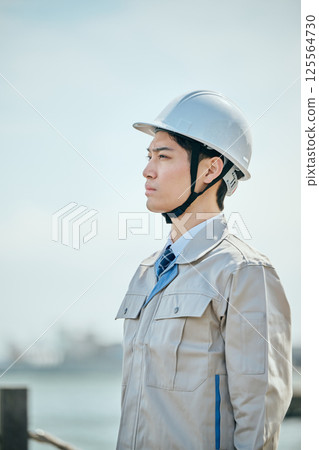 一位 20 多歲的年輕男子穿著工作服凝視遠方 一位 20 多歲的年輕男子穿著工作服凝視遠方 125564730