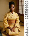 African American woman sitting upright in a bright kimono 125564909