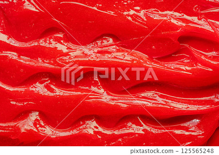 Red gel texture. Cosmetic clear liquid cream smudge. Skin care product sample closeup. Toothpaste or wax 125565248