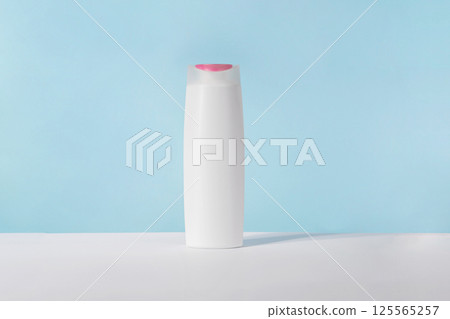 Shampoo white cosmetic bottle mockup on blue background. Hair product, bath soap or lotion packaging. Plastic cosmetics tube front view advertising mock up. Body hygiene cream 125565257
