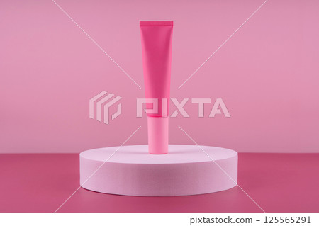 Pink cosmetic product on podium pedestal. Facial cream mockup on pink background, lotion in dispenser for woman skincare routine. Beauty moisturiser packaging. Lotion presentation 125565291