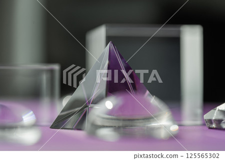 Crystal prism refracting light, magic crystals and pyramid, sphere and cube on purple background. Spiritual healing crystal practice. Feng Shui, good energy flow concept background.. Crystal prism refracting light, magic crystals and pyramid, sphere and cube on purple background. Spiritual healing crystal practice. Feng Shui, good energy flow concept background.. 125565302