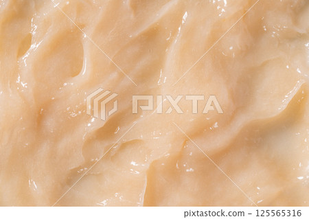 Hair conditioner cream background. Yellow cosmetic lotion moisturiser sample closeup. Body care balm, retinol serum, shampoo wavy texture. Skincare mask smear, creamy cleanser product 125565316
