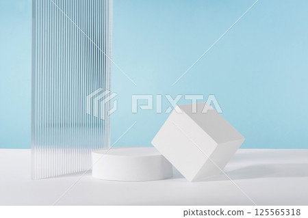 Acrylic ribbed plate, podium, background for cosmetic product packaging on blue backdrop. Showcase for jewellery presentation, display for perfume advertising, cosmetics branding scene Acrylic ribbed plate, podium, background for cosmetic product packaging on blue backdrop. Showcase for jewellery presentation, display for perfume advertising, cosmetics branding scene 125565318