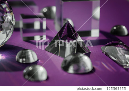 Crystal prism refracting light, magic crystals and pyramid, sphere and cube on purple background. Spiritual healing crystal practice. Feng Shui, good energy flow concept background.. Crystal prism refracting light, magic crystals and pyramid, sphere and cube on purple background. Spiritual healing crystal practice. Feng Shui, good energy flow concept background.. 125565355