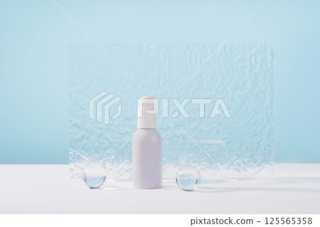 Cosmetic cream metallic pump bottle mockup on blue background with stylish props, glass balls and acrylic plate. Unbranded lotion white beauty product packaging. Product presentation Cosmetic cream metallic pump bottle mockup on blue background with stylish props, glass balls and acrylic plate. Unbranded lotion white beauty product packaging. Product presentation 125565358