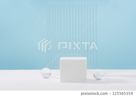 Acrylic plate, podium, background for cosmetic product packaging on blue backdrop with stylish props. Showcase for jewellery presentation, display for advertising, cosmetics branding scene Acrylic plate, podium, background for cosmetic product packaging on blue backdrop with stylish props. Showcase for jewellery presentation, display for advertising, cosmetics branding scene 125565359