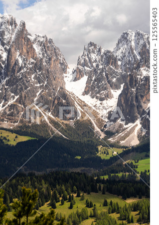 Majestic mountain landscape with snowy peaks and lush green valleys near Valley of Funes at Dolomites, Italy Majestic mountain landscape with snowy peaks and lush green valleys near Valley of Funes at Dolomites, Italy 125565403