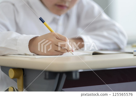 The hands of a 9-year-old boy studying with a pencil 125565576