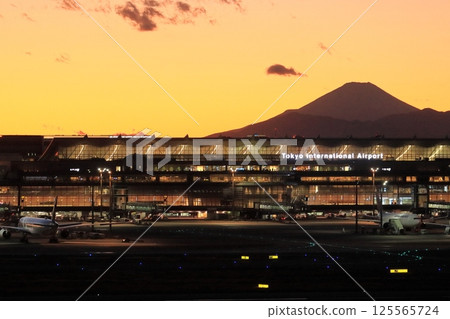 Haneda Airport with the silhouette of Mt. Fuji in the background, and Terminal 3 lit up with the sunset in the background 125565724