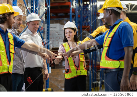 Group of warehouse workers Join hands each other, showing teamwork and camaraderie after finishing significant task successfully. Atmosphere lively and encouraging. Group of warehouse workers Join hands each other, showing teamwork and camaraderie after finishing significant task successfully. Atmosphere lively and encouraging. 125565905