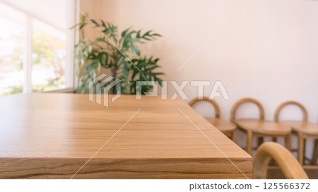 Closeup of natural wooden tabletop with blurred view of stools indoor plant and bright minimal modern interior Closeup of natural wooden tabletop with blurred view of stools indoor plant and bright minimal modern interior 125566372