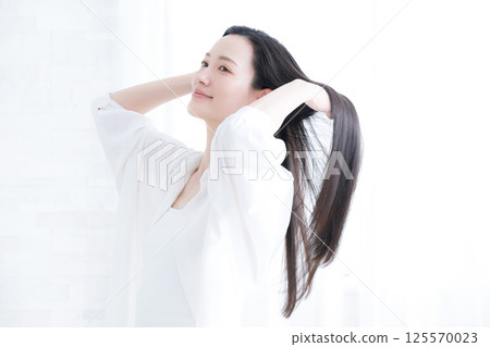 一位年輕女子飄逸的長黑髮、護髮和美容的美麗形象，梳理她的頭髮 125570023