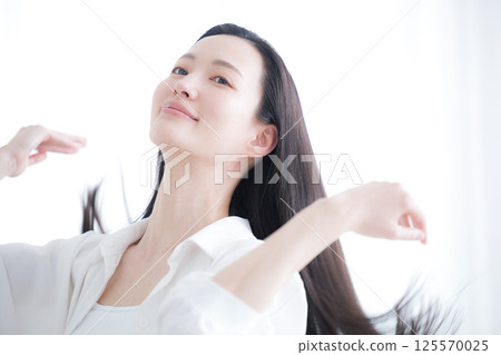 一位年輕女子飄逸的長黑髮、護髮和美容的美麗形象，梳理她的頭髮 125570025