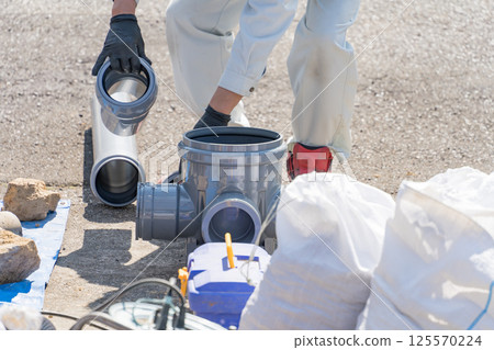 A worker installing a public sewage manhole during sewer piping work 125570224