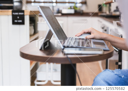 Focus on woman hand holding computer mouse while working on laptop. Focus on woman hand holding computer mouse while working on laptop. 125570582