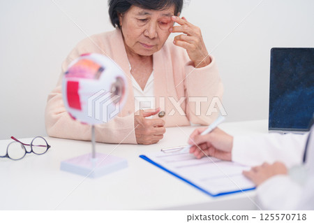 Elderly Patient consulting Doctor to Eye disease, Senior Medical Diagnosis. Anatomy Eye model for Cataract, Glaucoma, Age Related Macular Degeneration, Diabetic Retinopathy, Vitreous, health concept Elderly Patient consulting Doctor to Eye disease, Senior Medical Diagnosis. Anatomy Eye model for Cataract, Glaucoma, Age Related Macular Degeneration, Diabetic Retinopathy, Vitreous, health concept 125570718
