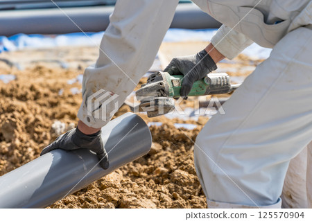 一名建築工人使用圓盤磨床去除下水管道的毛刺 125570904