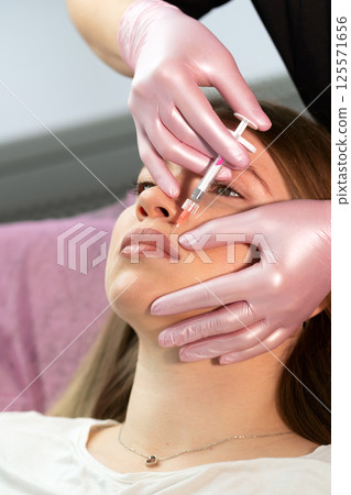 Aesthetician injects lip filler near patient's nasolabial fold Aesthetician injects lip filler near patient's nasolabial fold 125571656