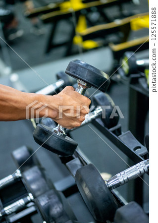 Hand Gripping Dumbbell from Rack in Fitness Center Hand Gripping Dumbbell from Rack in Fitness Center 125571888