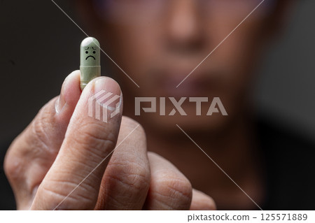 Man Holding Green Pill with Sad Face Drawing 125571889