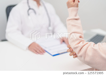 Elderly Woman having elbow ache and consulting doctor in hospital. muscle pain due to lateral epicondylitis or tennis elbow. injury, Health and medical consultation concept 125571995