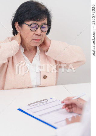 Elderly Woman having Shoulder and Neck and consulting doctor in hospital. Muscle painful due to Myofascial pain syndrome and Fibromyalgia, rheumatism, Scapular pain, Cervical Spine. ergonomic concept Elderly Woman having Shoulder and Neck and consulting doctor in hospital. Muscle painful due to Myofascial pain syndrome and Fibromyalgia, rheumatism, Scapular pain, Cervical Spine. ergonomic concept 125572026