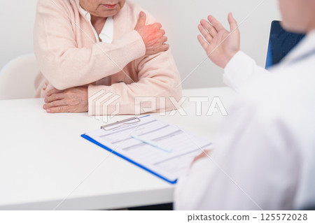 Elderly Woman having Shoulder and Neck and consulting doctor in hospital. Muscle painful due to Myofascial pain syndrome and Fibromyalgia, rheumatism, Scapular pain, Cervical Spine. ergonomic concept Elderly Woman having Shoulder and Neck and consulting doctor in hospital. Muscle painful due to Myofascial pain syndrome and Fibromyalgia, rheumatism, Scapular pain, Cervical Spine. ergonomic concept 125572028