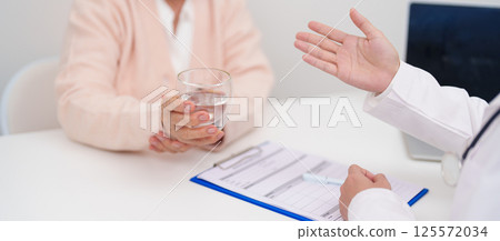 Senior woman with Tremor hand during taking glass of water in hospital. Parkinson disease April awareness month, Carpal Tunnel Syndrome, rheumatoid and brain injury and Neurological disorder concept 125572034