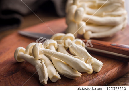 Raw white shimeji mushrooms on wooden cutting board. 125572510