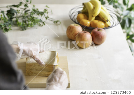 Woman cutting a sandwich, dining table with fruit 125573400