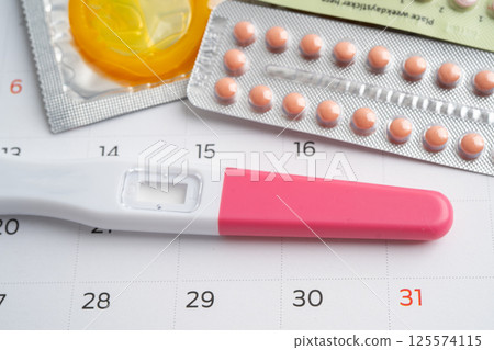 Pregnancy test and birth control pills on calendar, contraception health and medicine. 125574115