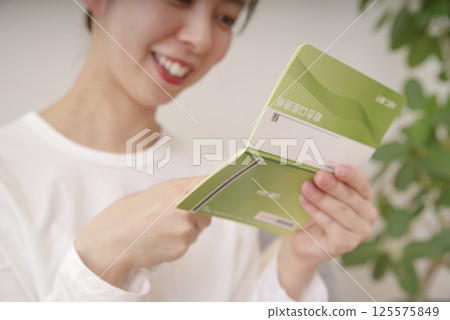 一位女士微笑著看著她的存摺 一位女士微笑著看著她的存摺 125575849