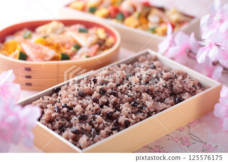 Red rice, eaten during celebratory events in Japan, photographed with cherry blossoms on a pink background. 125576175