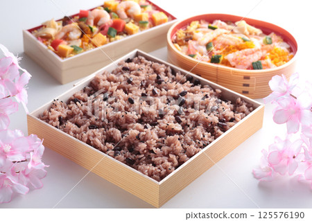 Red rice, eaten during celebratory events in Japan, photographed with cherry blossoms on a pink background. 125576190